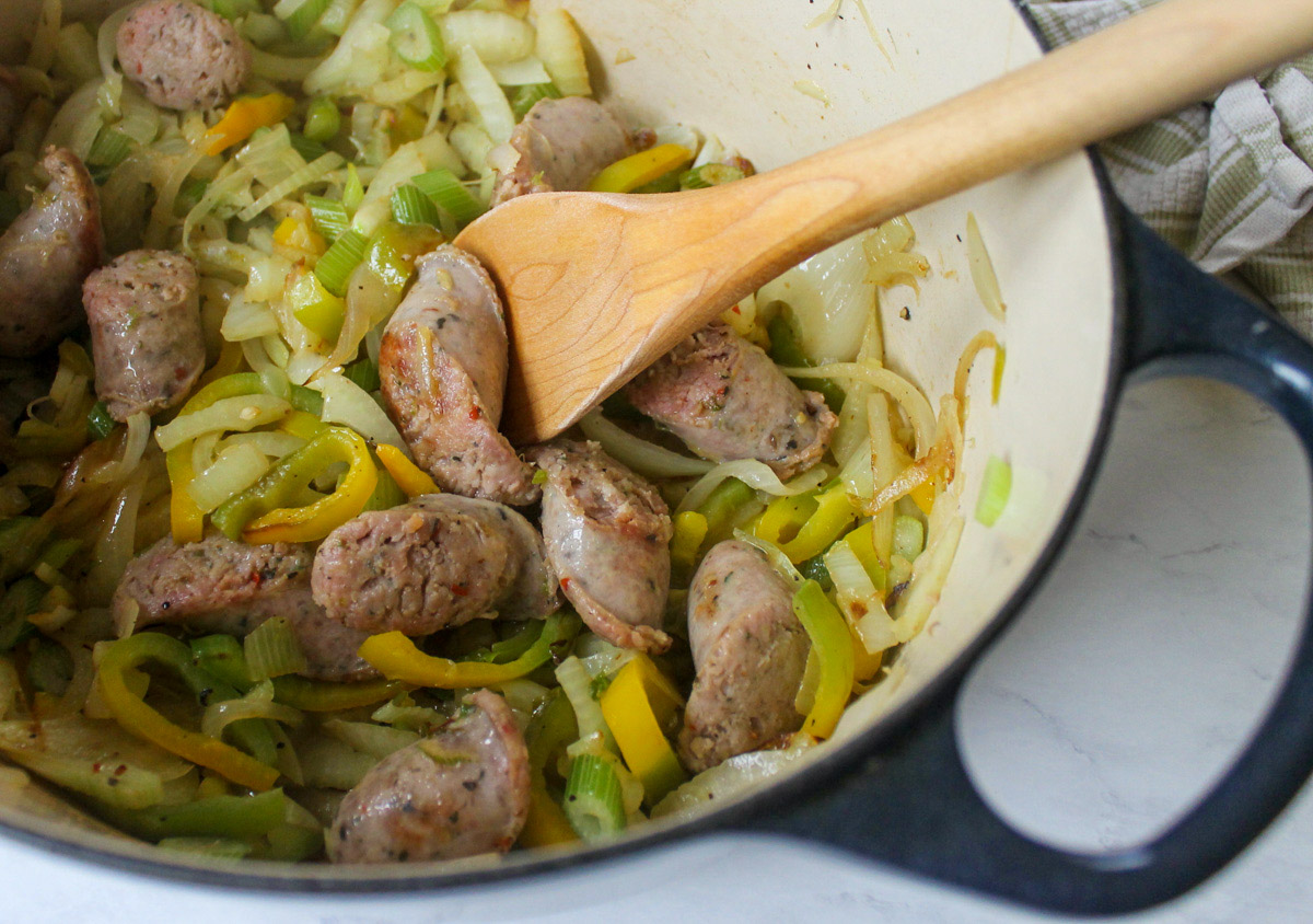 Sautéing Italian sausage links with peppers, onions, and fennel.