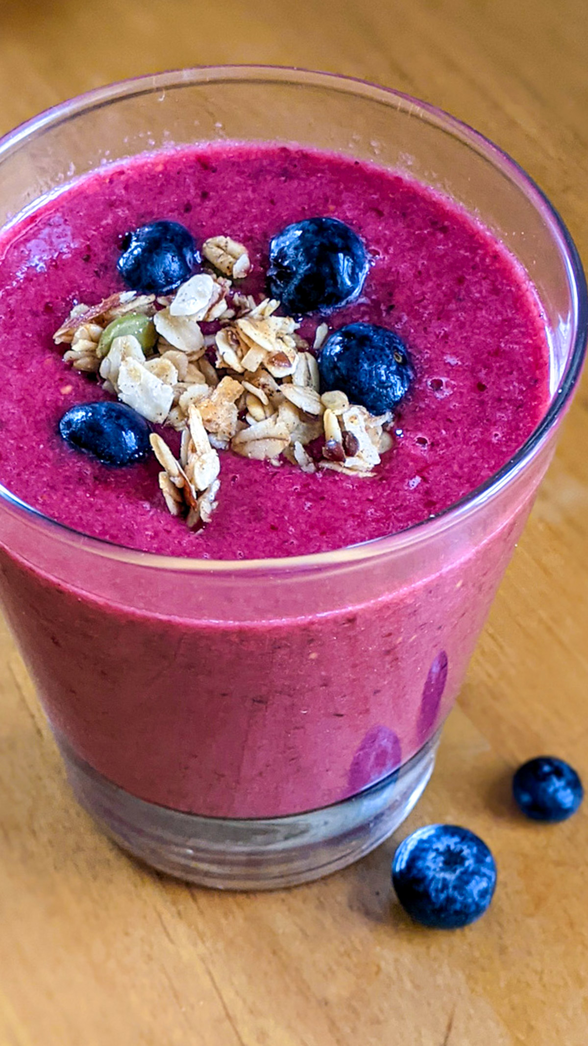 Bright pink berry smoothie with blueberry and granola topping.