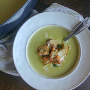 A bowl of spring asparagus soup next to the soup pot.