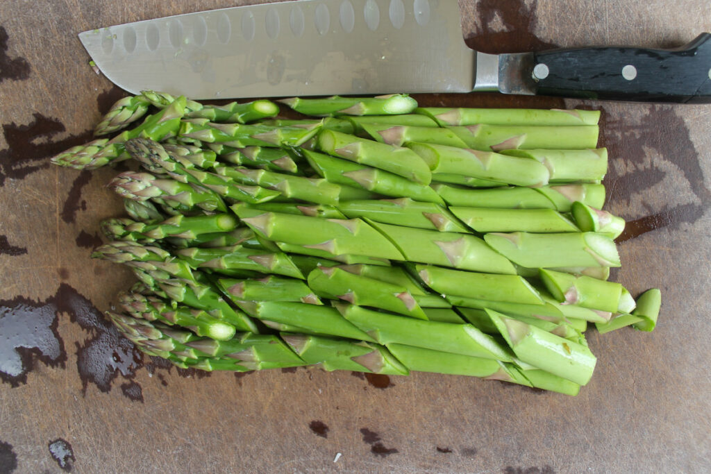 Diagonally sliced asparagus on a cutting board.