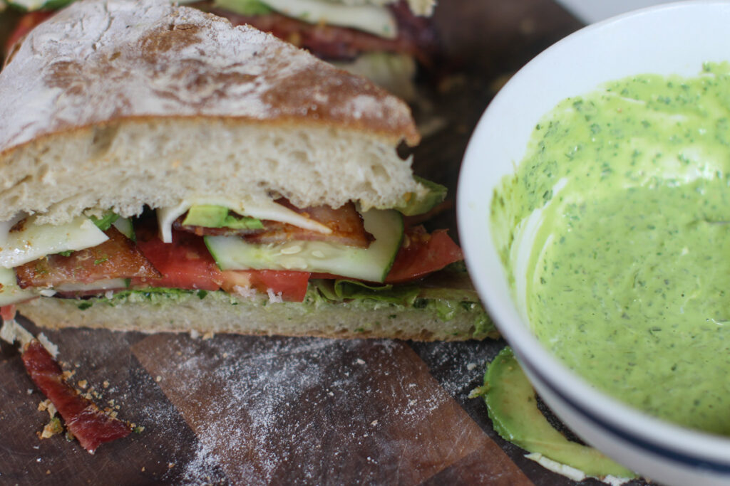 A wedge of garden BLT's next to a bowl of pesto aioli.