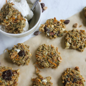 Several zucchini banana cookies on parchment paper with a bowl of ice cream and cookies.