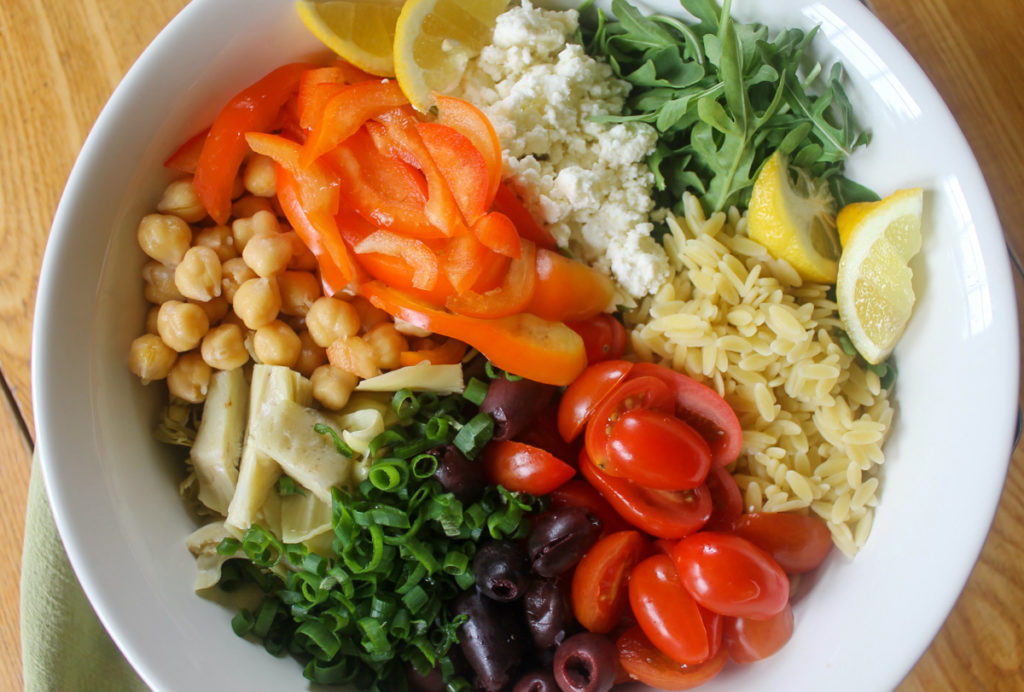 Lemon Orzo Pasta Salad Ingredients in a bowl ready to mix with dressing.