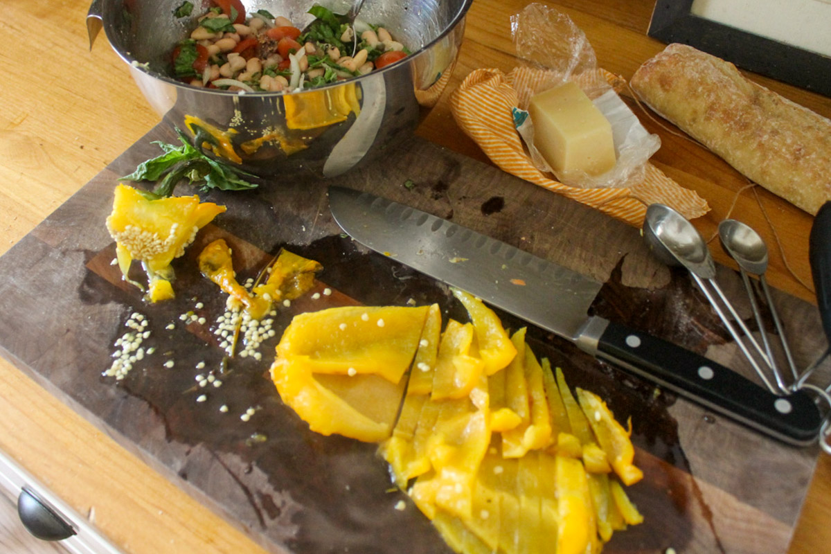 Slicing a yellow roasted bell pepper to add to the bowl of white bean bruschetta appetizer.