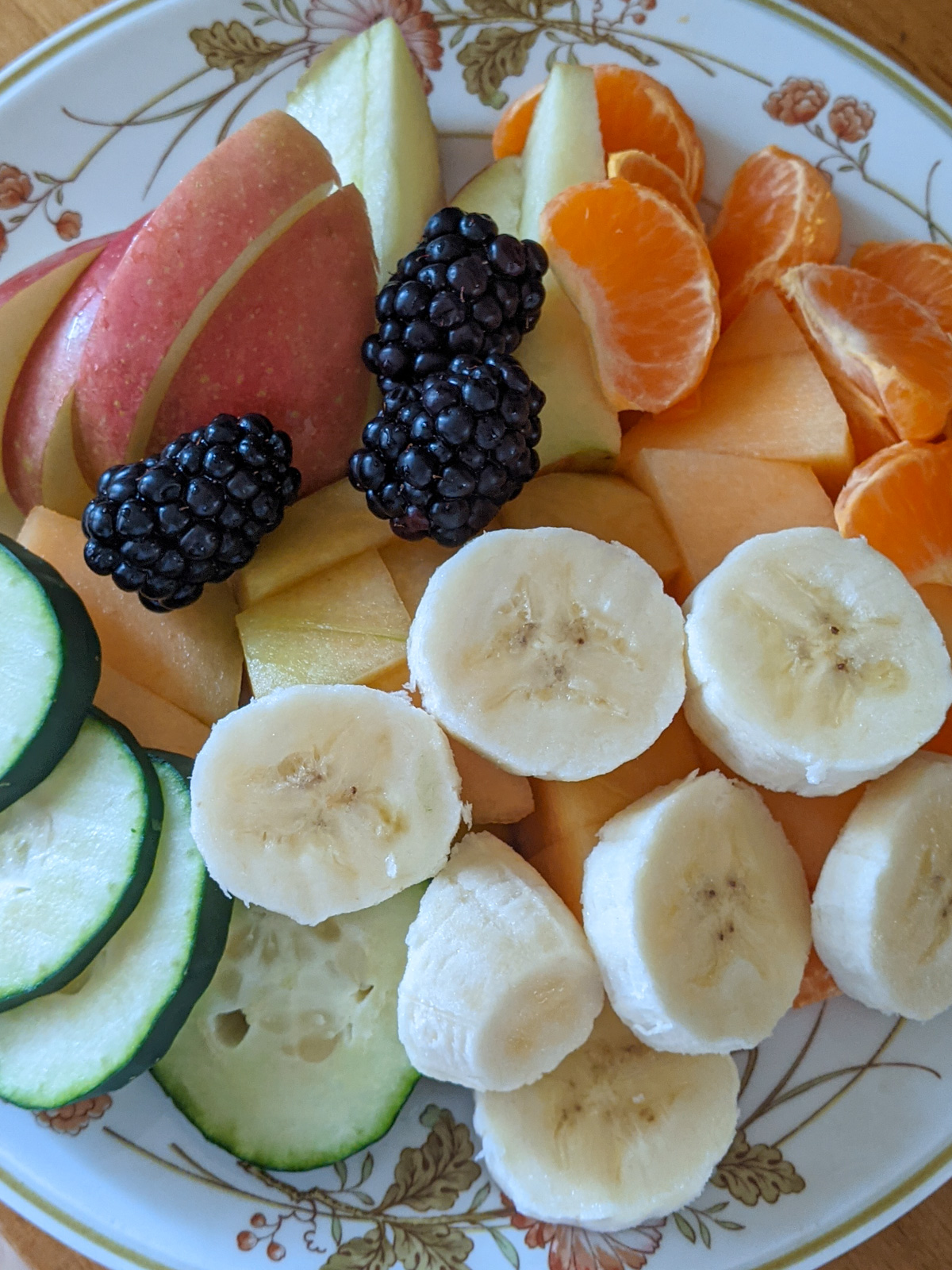 Bedtime snacks for toddlers with apple, oranges, banana, blackberries, cucumber.