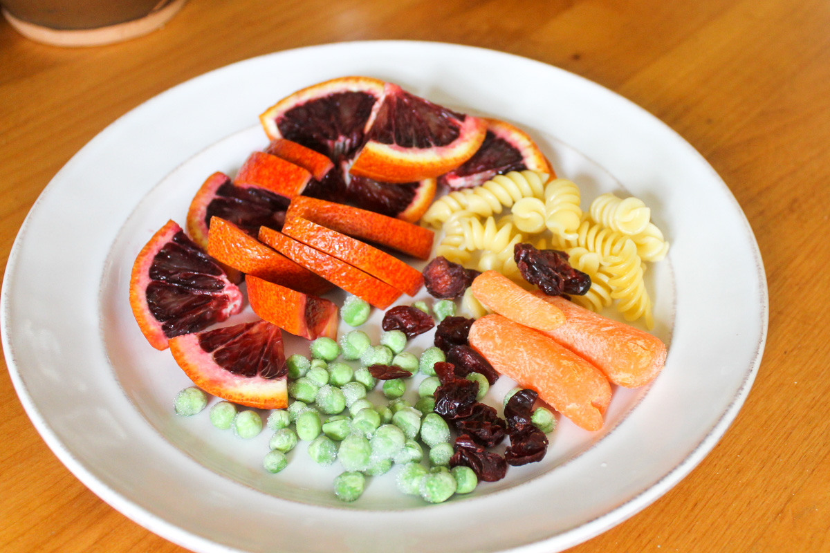 Sliced blood oranges, peas, carrots, dried cranberry and leftover rotini pasta for the kid's snack.