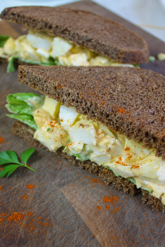 Egg salad sandwiches on dark rye bread with lettuce.