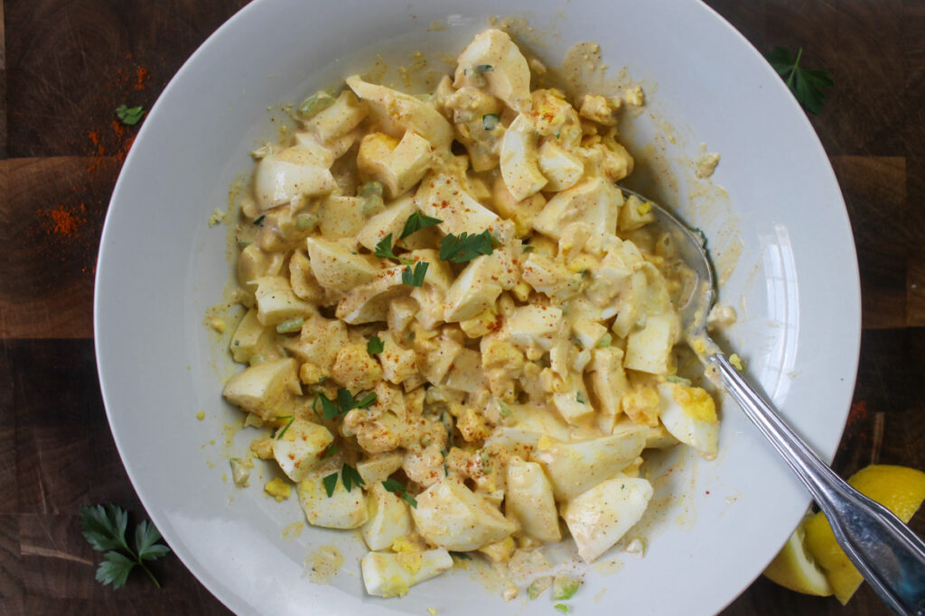 Bowl of chopped hard boiled eggs mixed with dressing for egg salad.