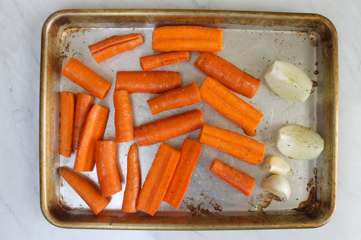 Raw carrots, onions, and garlic ready to roast for carrot hummus.