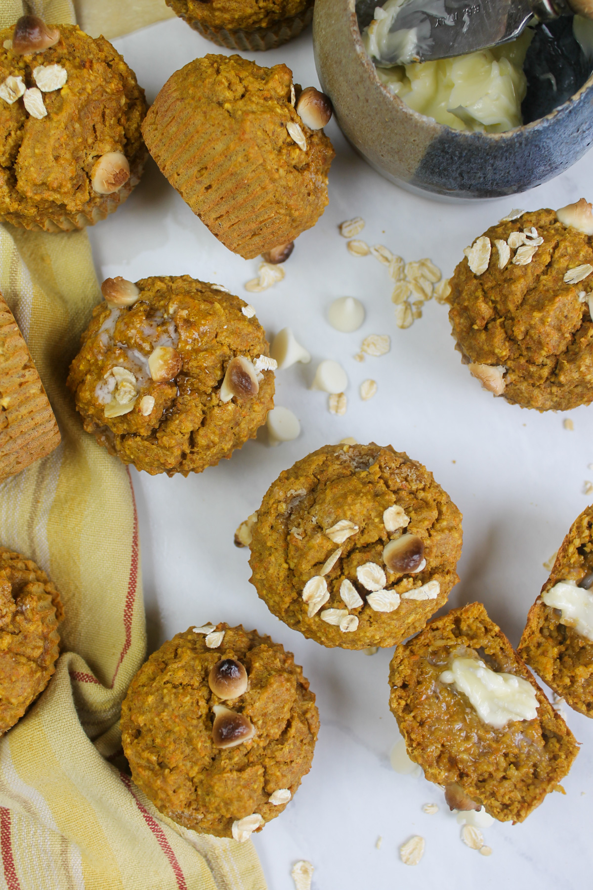 Healthy banana carrot muffins on a white counter and a yellow dish towel.