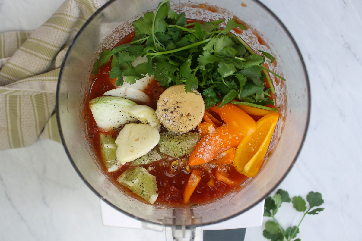 All salsa ingredients in a bowl of a food processor, ready to be processed.