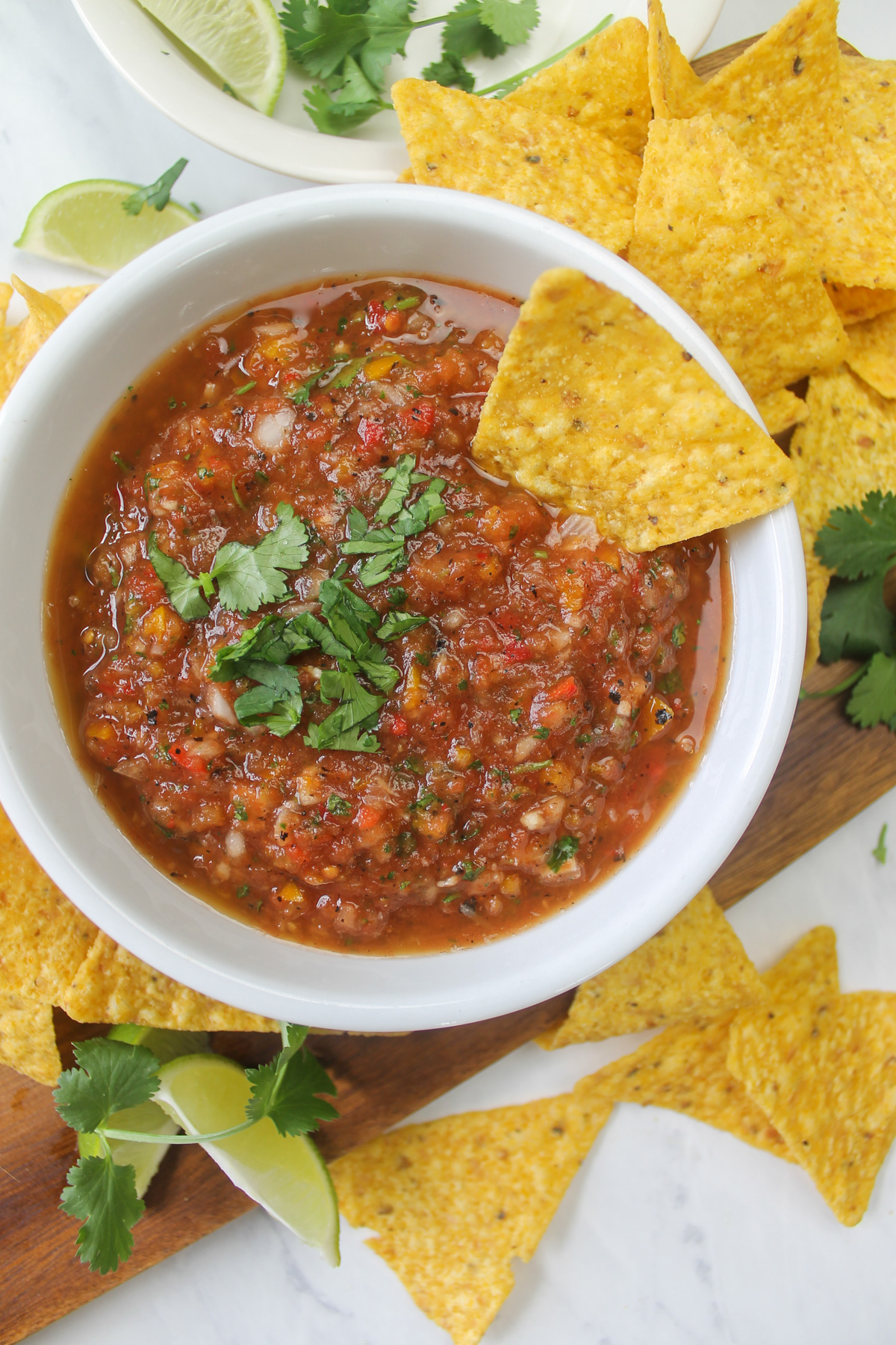 A white bowl of salsa surrounded by chips.