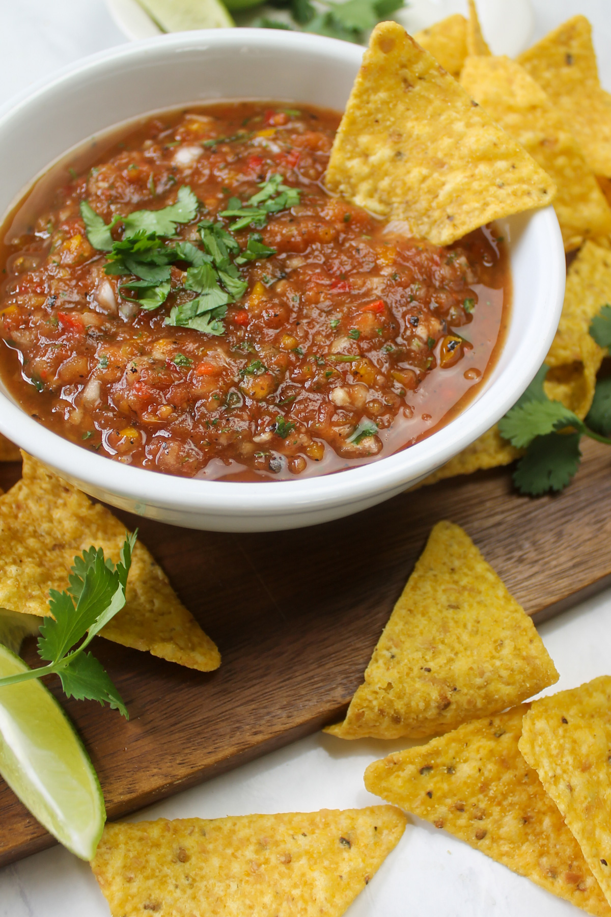 A bowl of salsa with yellow corn tortilla chips to dip.