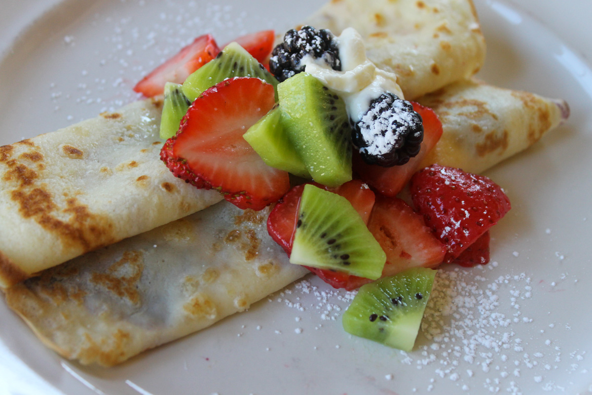 Crepes rolled and piled with sliced kiwi, strawberry and blackberry and a dusting of powdered sugar.