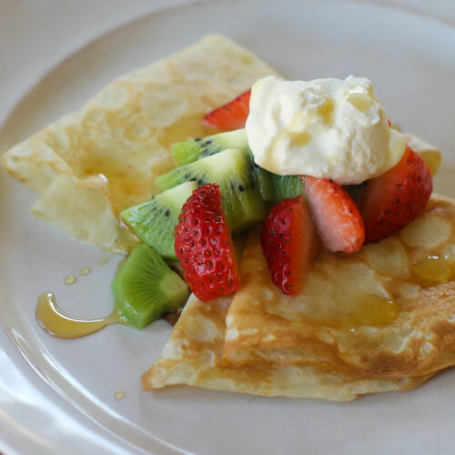 Crepes folded and topped with strawberry, kiwi, fresh whipped cream and a drizzle of maple syrup.