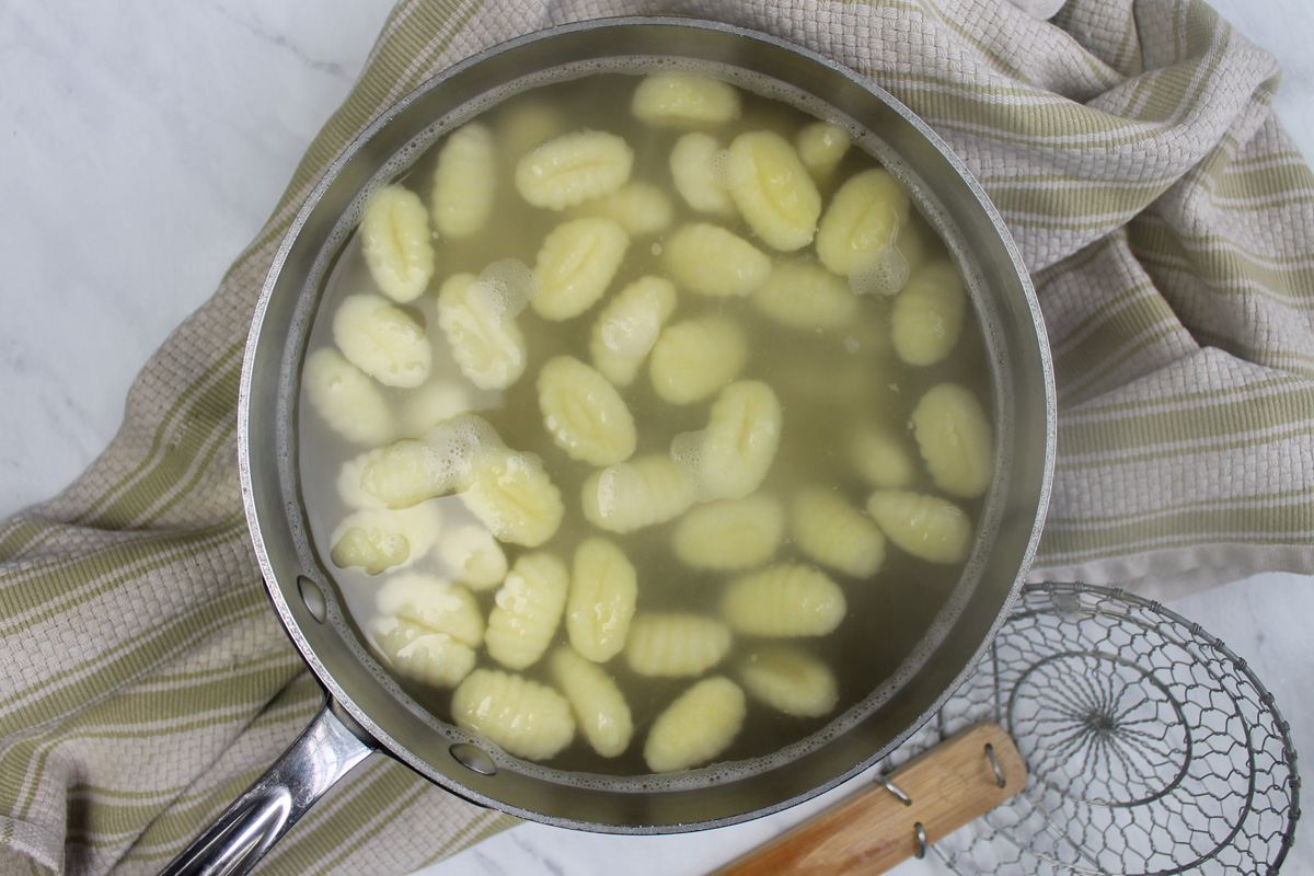 Boiled gnocchi floating in water ready to drain.