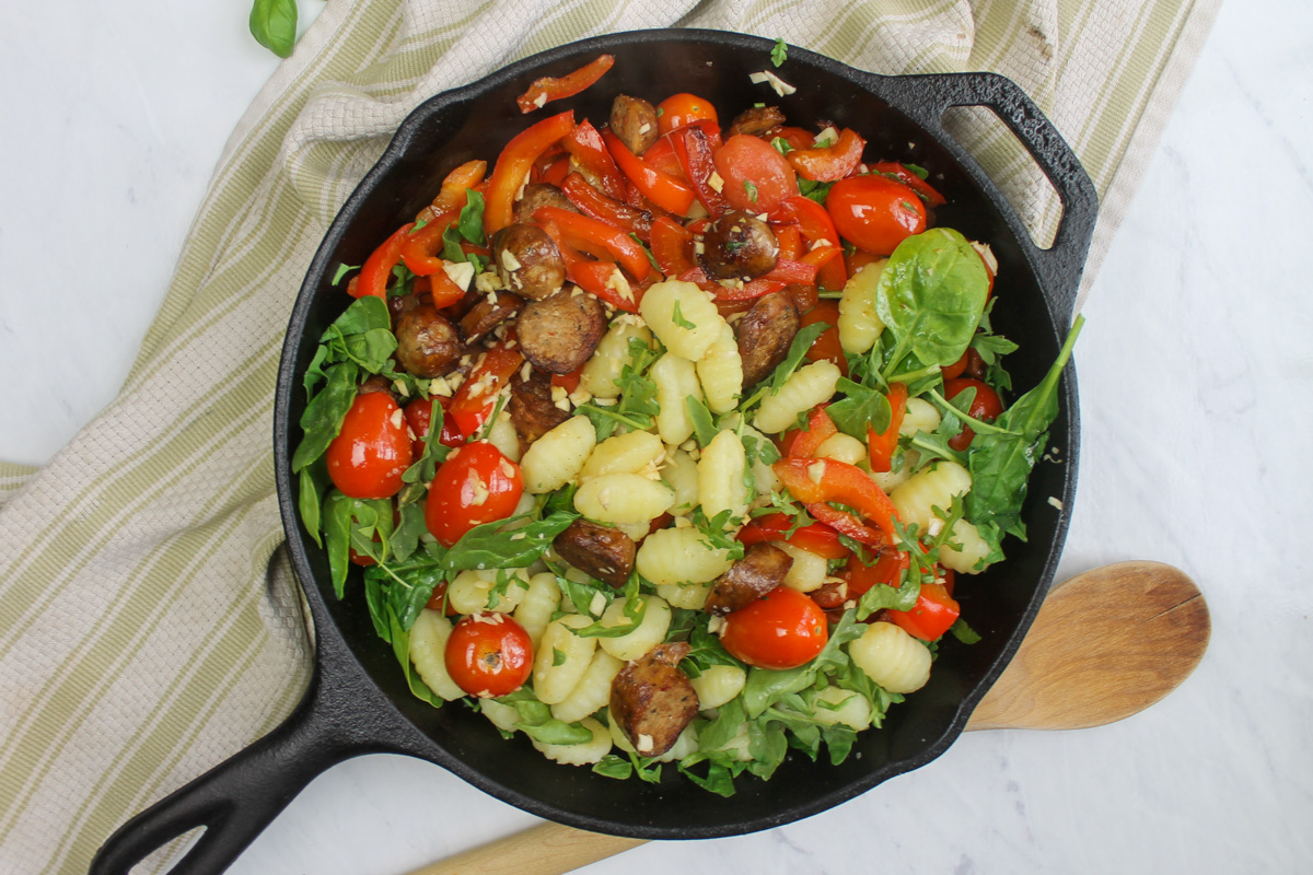 Boiled gnocchi, garlic, and arugula or spinach added to the skillet with the sausage, peppers, cherry tomato and pine nuts.