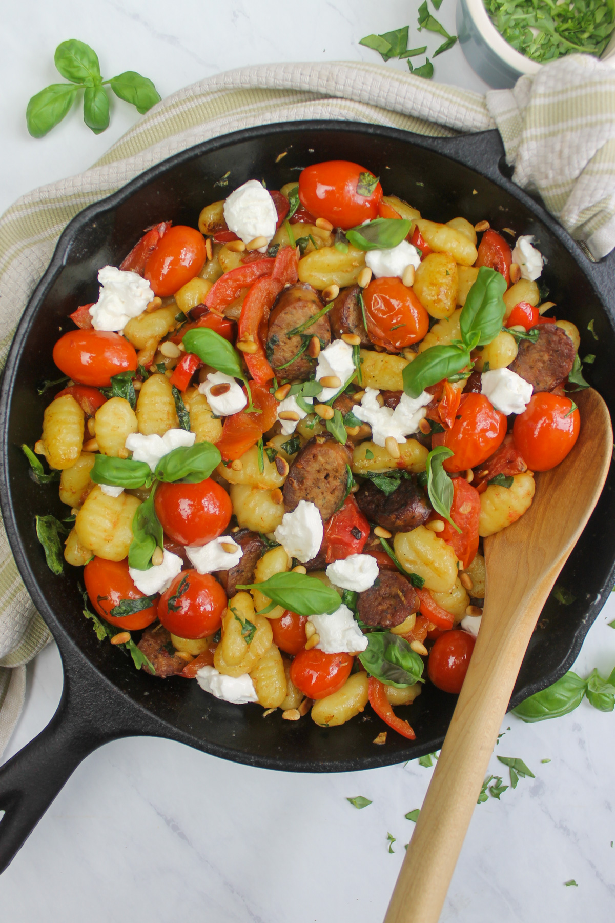 The finished gnocchi dish served in the cast iron skillet and garnished with basil and goat cheese.