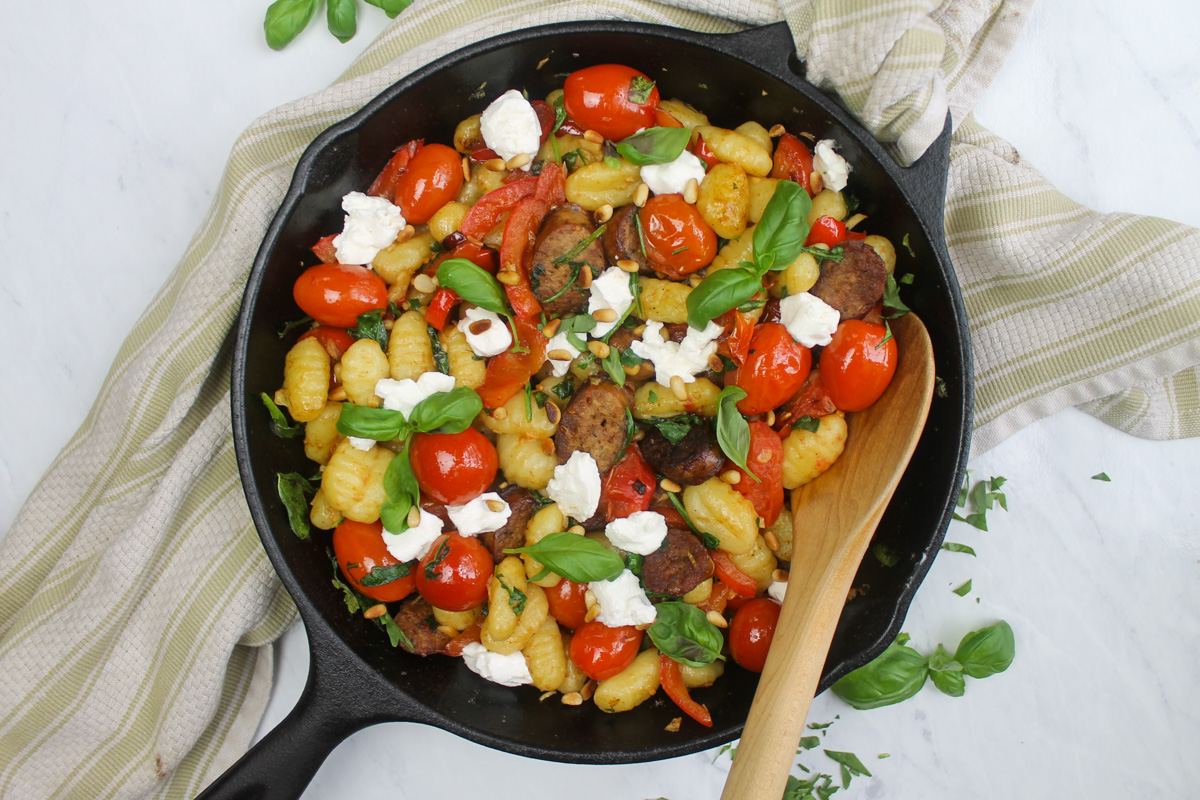 Skillet gnocchi with tomato, bell pepper, sausage and greens, ready to serve.