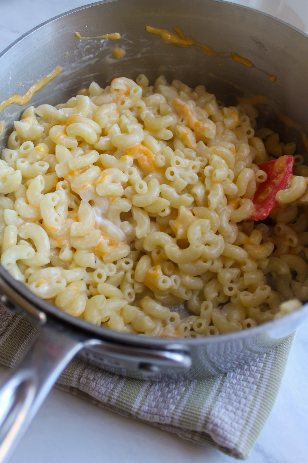 Mixing mac and cheese in a pot to the shredded cheese melts in.