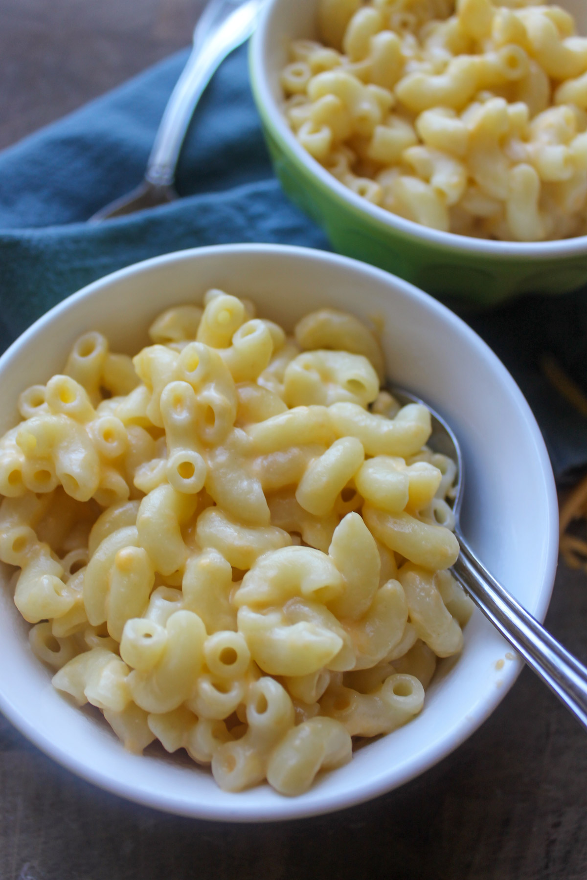 Two small bowls of mac and cheese made with yogurt and shredded cheese.