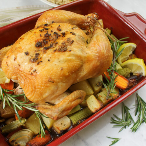 Whole roasted chicken with root vegetables and fresh rosemary.