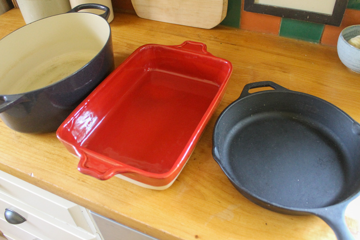 A dutch oven, a casserole dish, and a cast iron skillet, options for roasting a whole chicken.