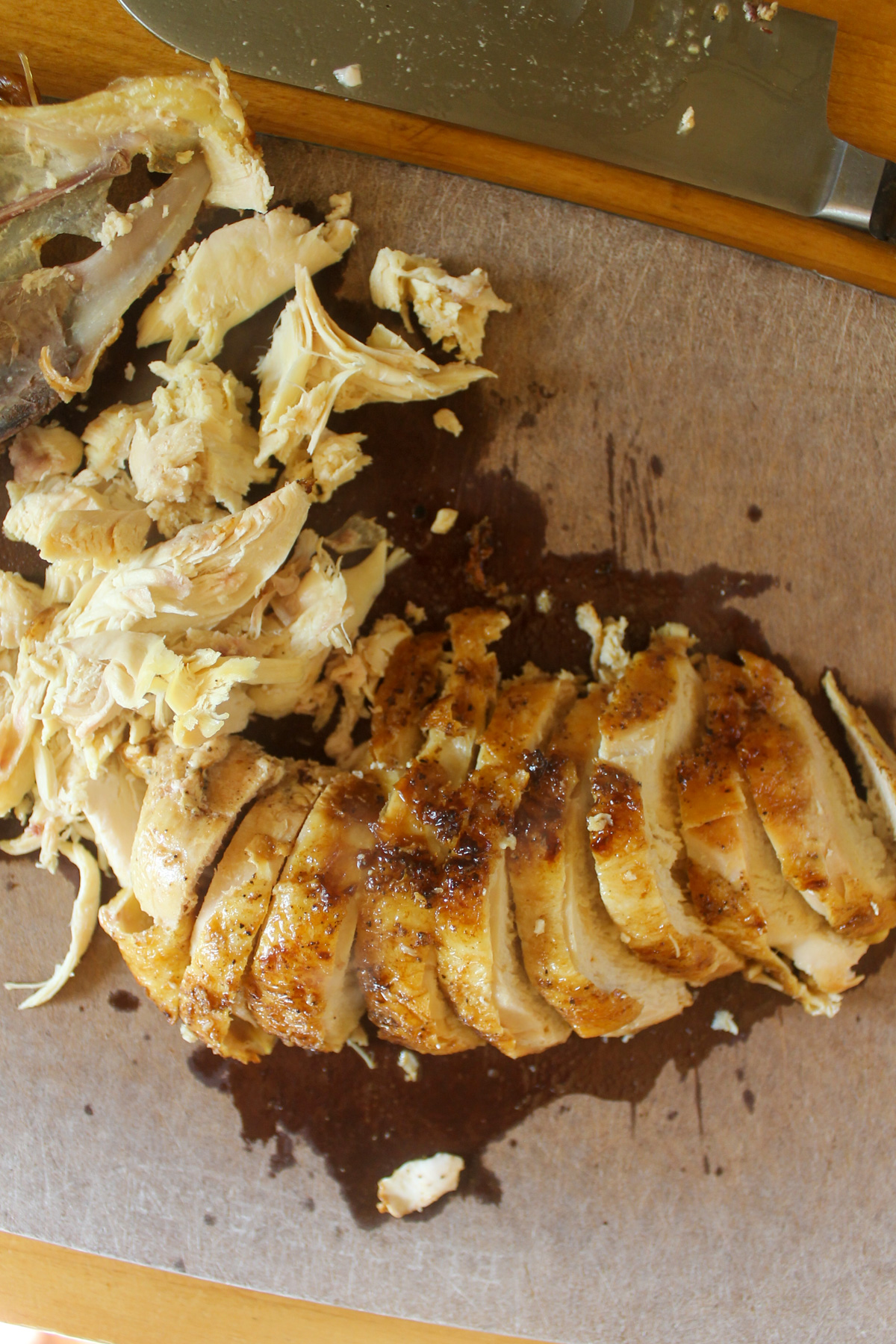 Slicing a chicken breast on a cutting board with seared crispy skin.