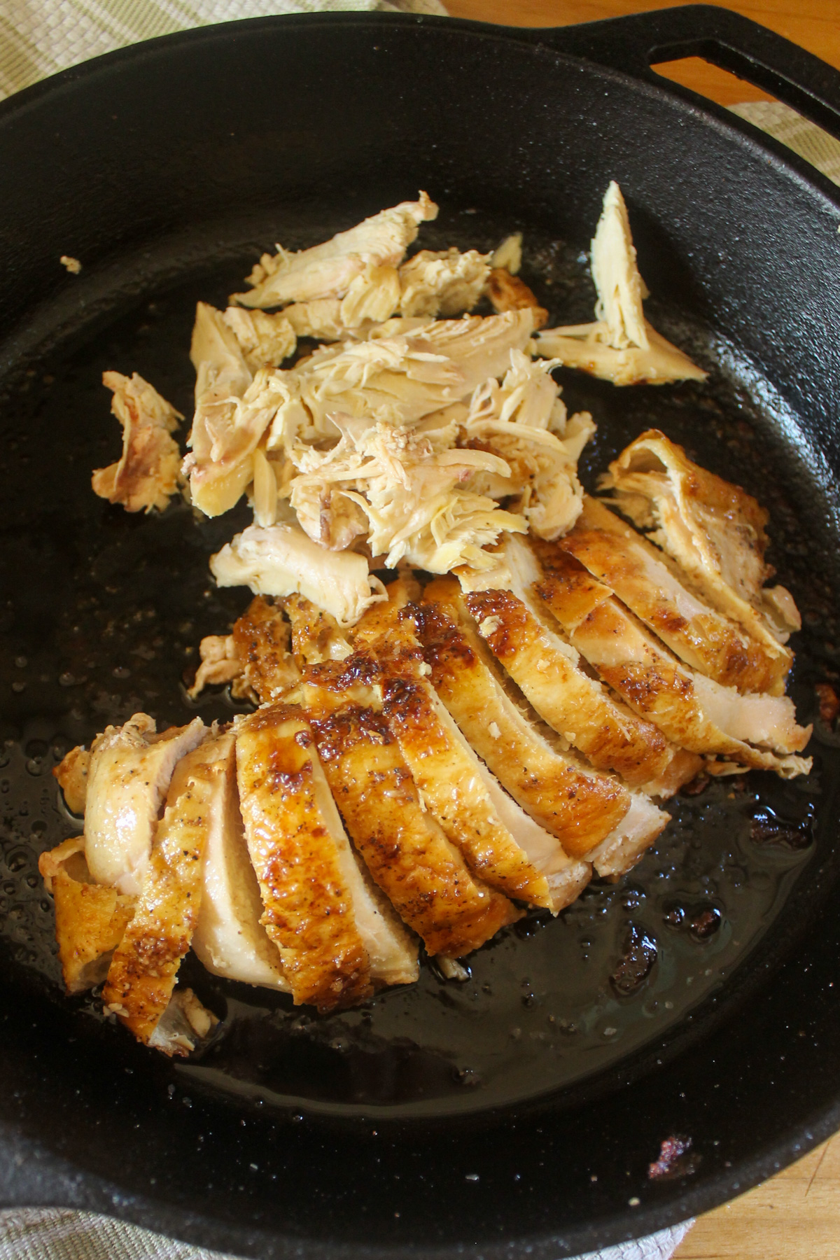 The sliced chicken breast meat in a cast iron skillet.
