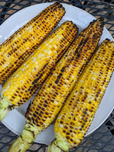 A plate of charred corn on the cob grilled with butter and salt..
