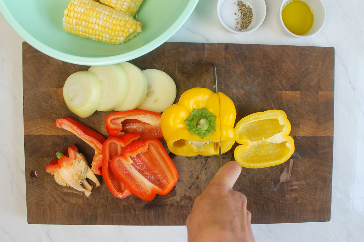 Slicing peppers, onions, and corn on the cob to grill for fajitas.