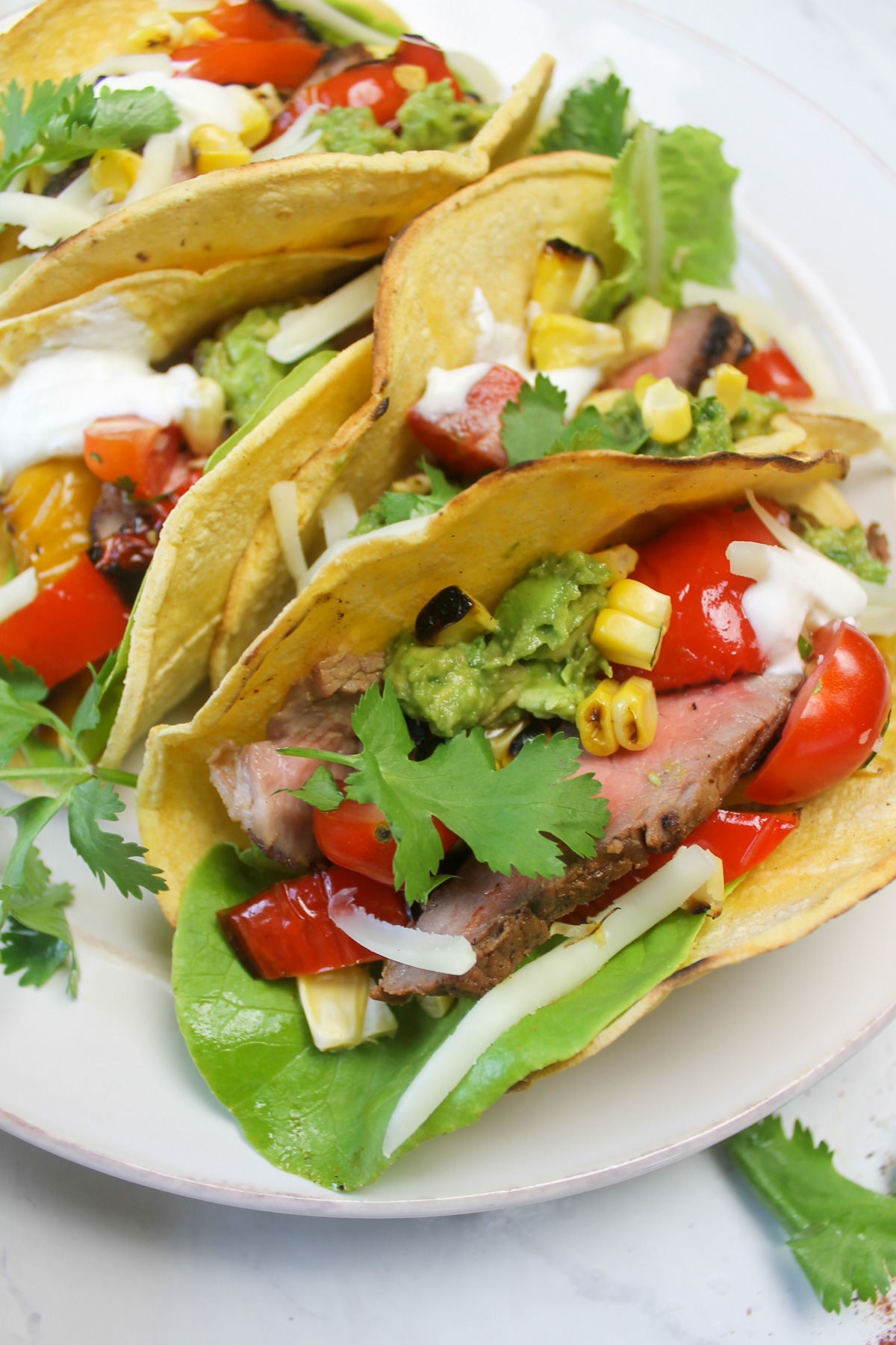 A plate of finished steak fajita tacos with guacamole and pico de gallo.