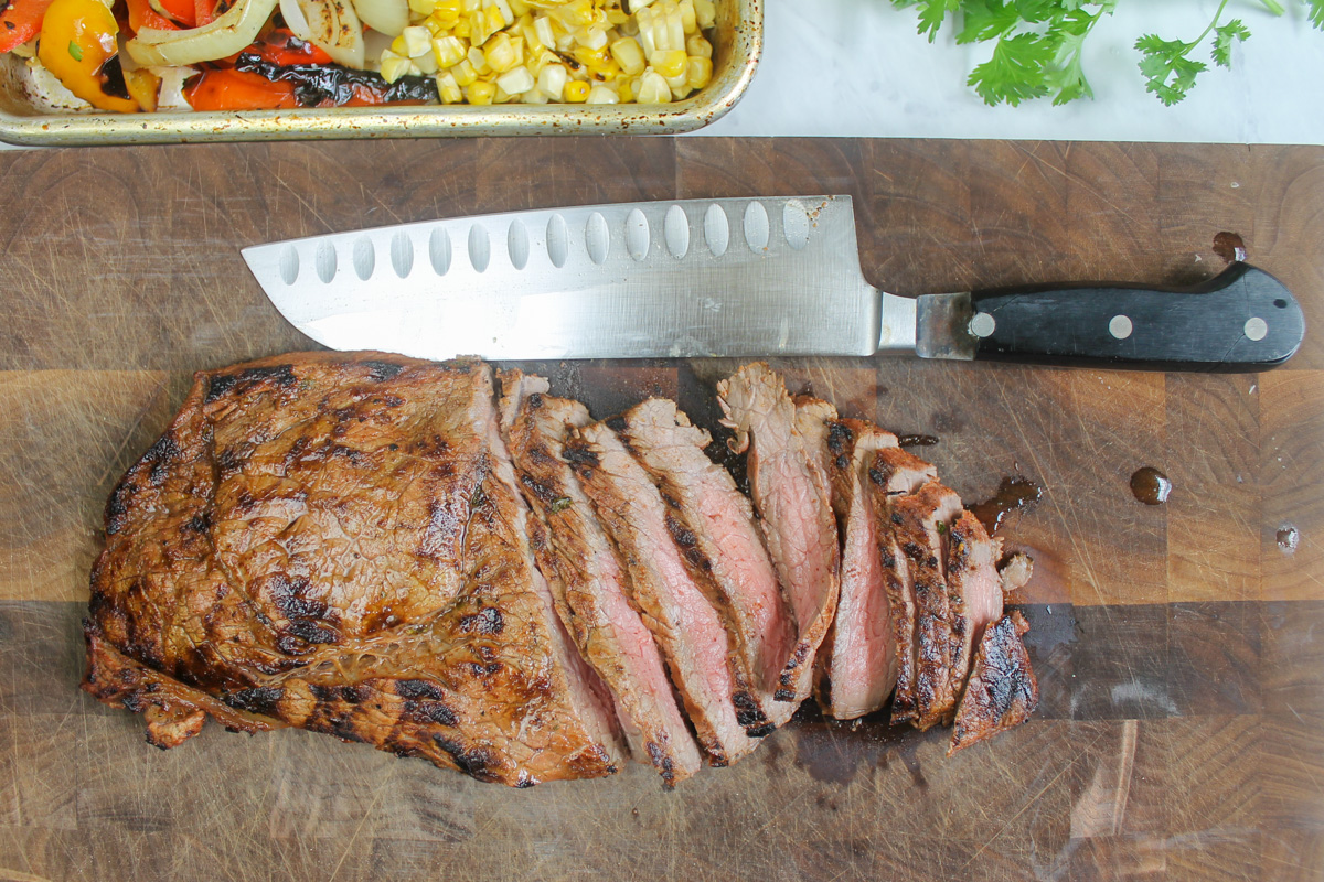 Slicing medium rare steak on a cutting board.