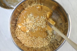 A large bowl with the peanut butter marshmallow mixing in with the rice krispies and other dry ingredients.