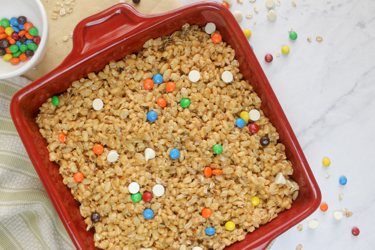 A square red pan with the finished protein rice krispy treats with M&M's and white chocolate chips.