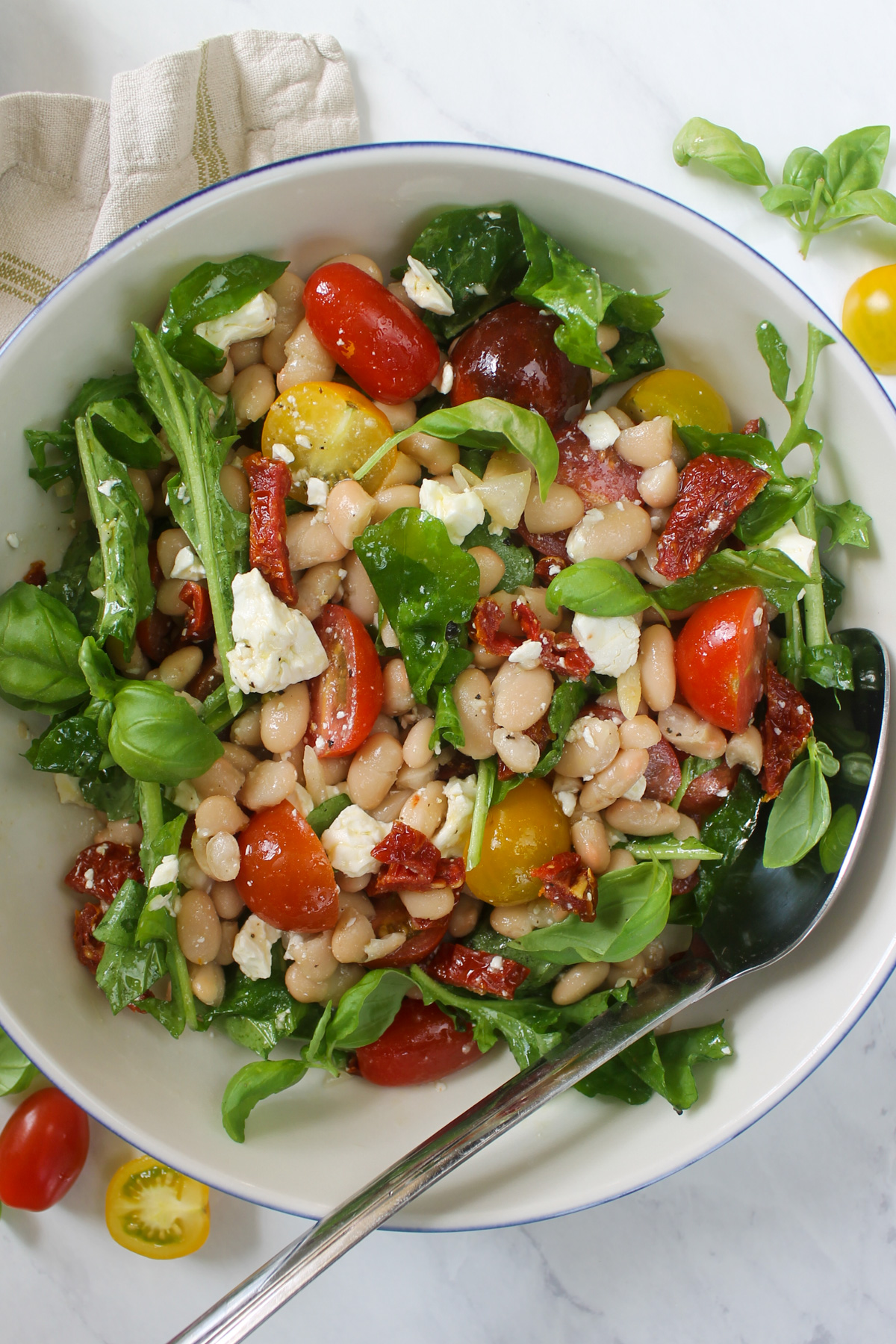 The finished Tomato Feta White Bean Salad mixed with dressing in a white bowl.