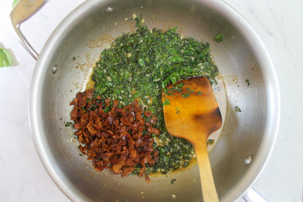 Adding the cooked bacon back to the pasta sauce with kale.