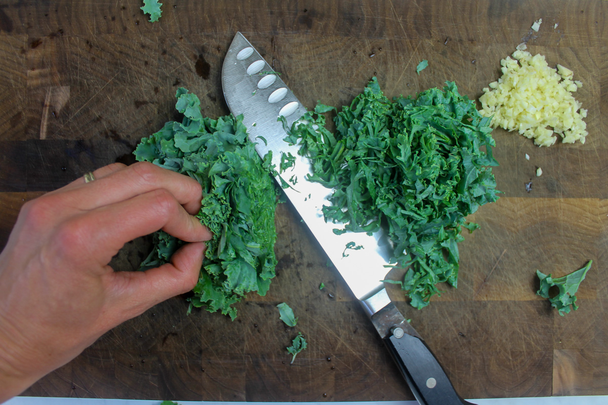Chopping kale by forming a tight pile and running the knife through to slice it.