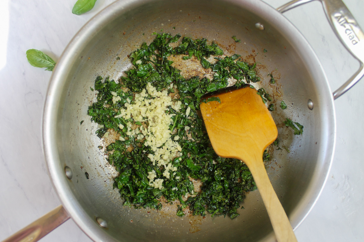 Adding garlic to the sautéed kale.