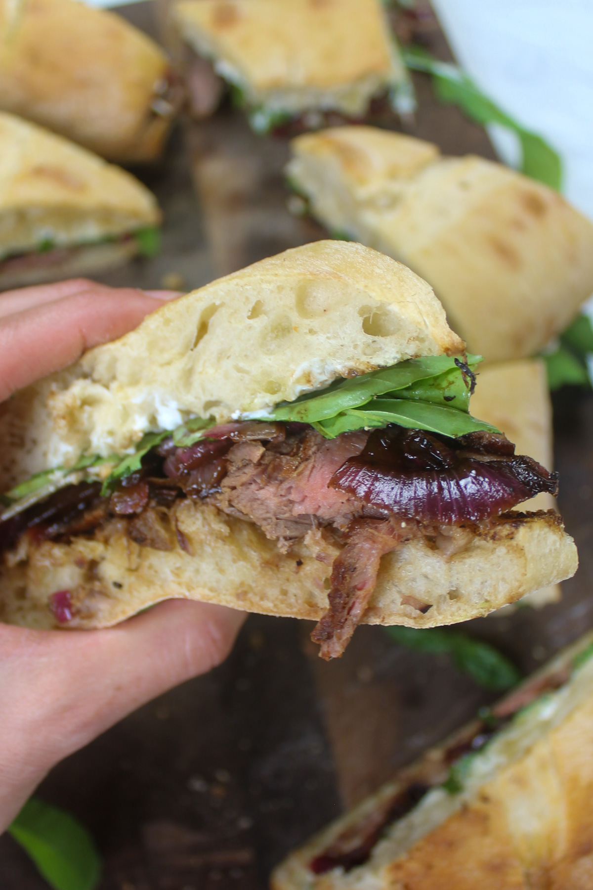 Holding a wedge of steak sandwich.