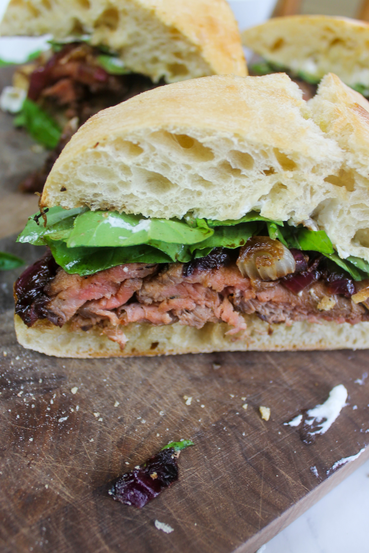 A wedge of steak sandwich with goat cheese and arugula.