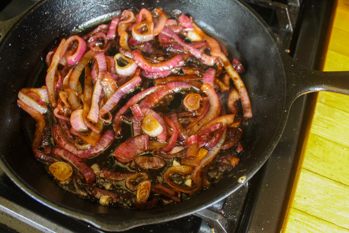 A cast iron skillet with caramelized onions in balsamic vinegar.