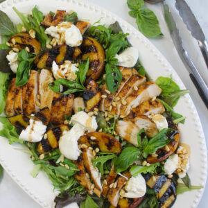A dinner salad platter with peaches, chicken, and burrata cheese.