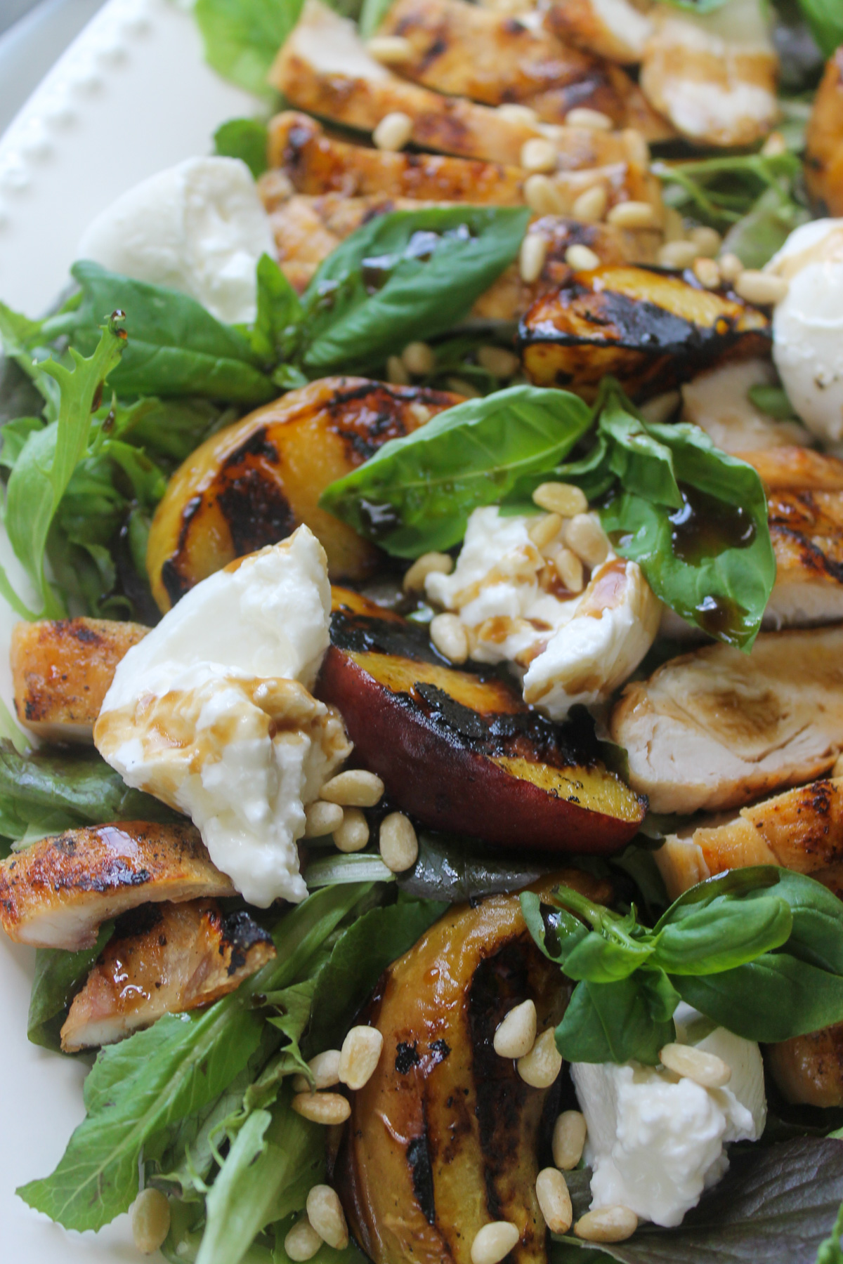 Close up of the grilled peaches and creamy burrata cheese on the salad.