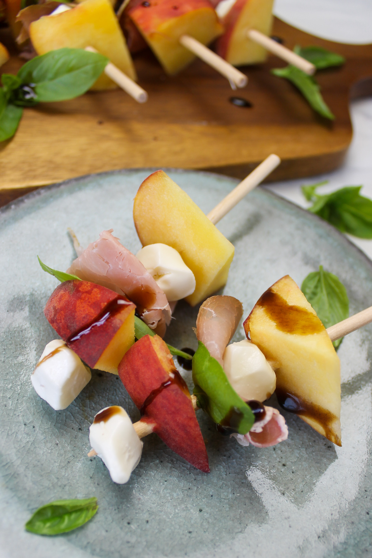 A small blue plate of 2 peach prosciutto appetizer skewers.