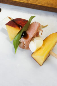 A close up of 1 peach caprese skewer with basil.