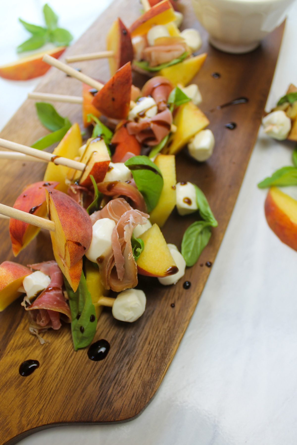 A serving board of Colorado peaches on appetizer skewers with mozzarella and prosciutto.