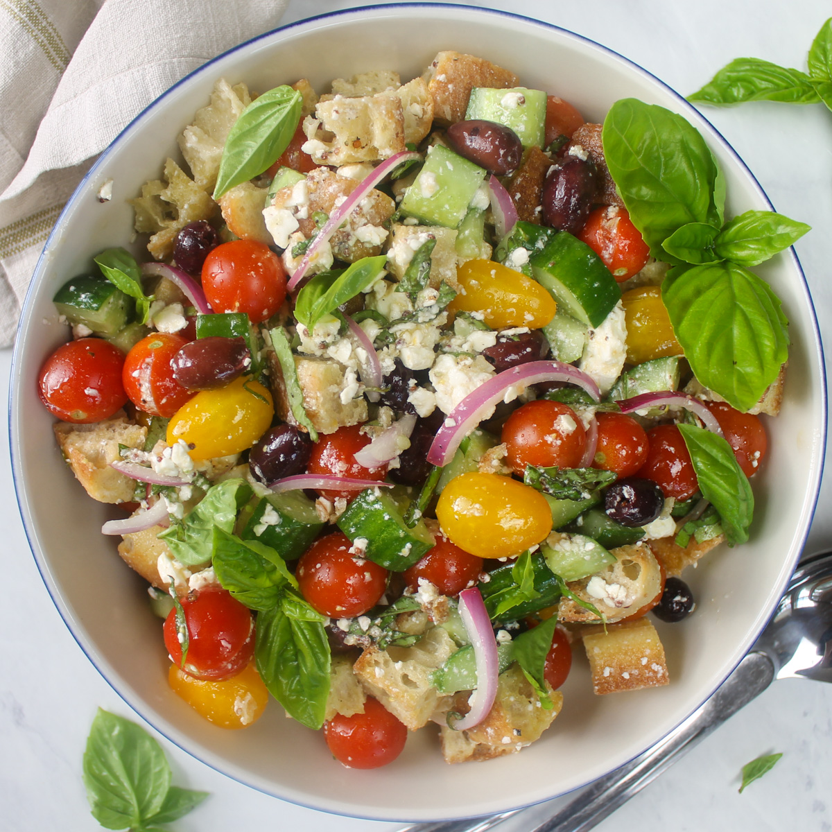 Bowl of summer panzanella salad with feta, cucumber and basil.