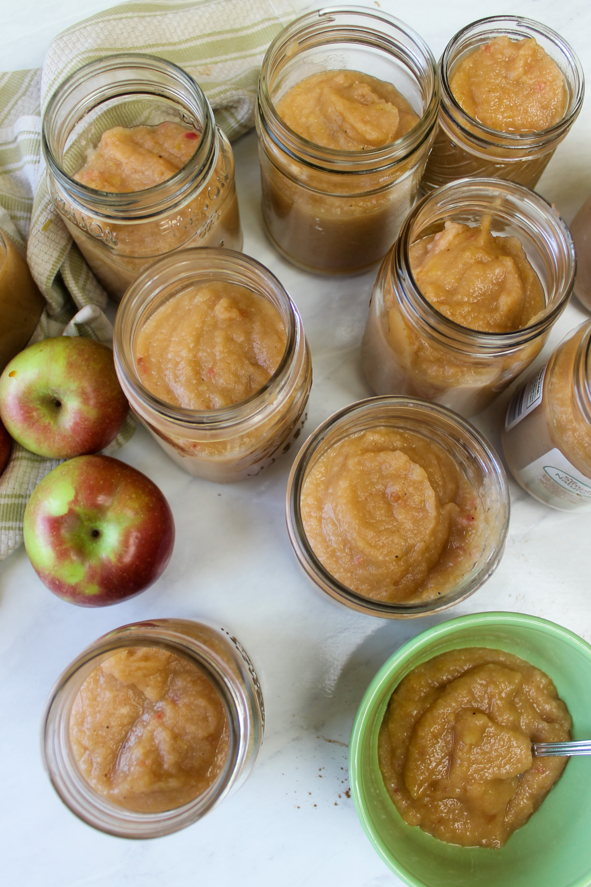 A green bowl of no sugar applesauce and several jars for the freezer.