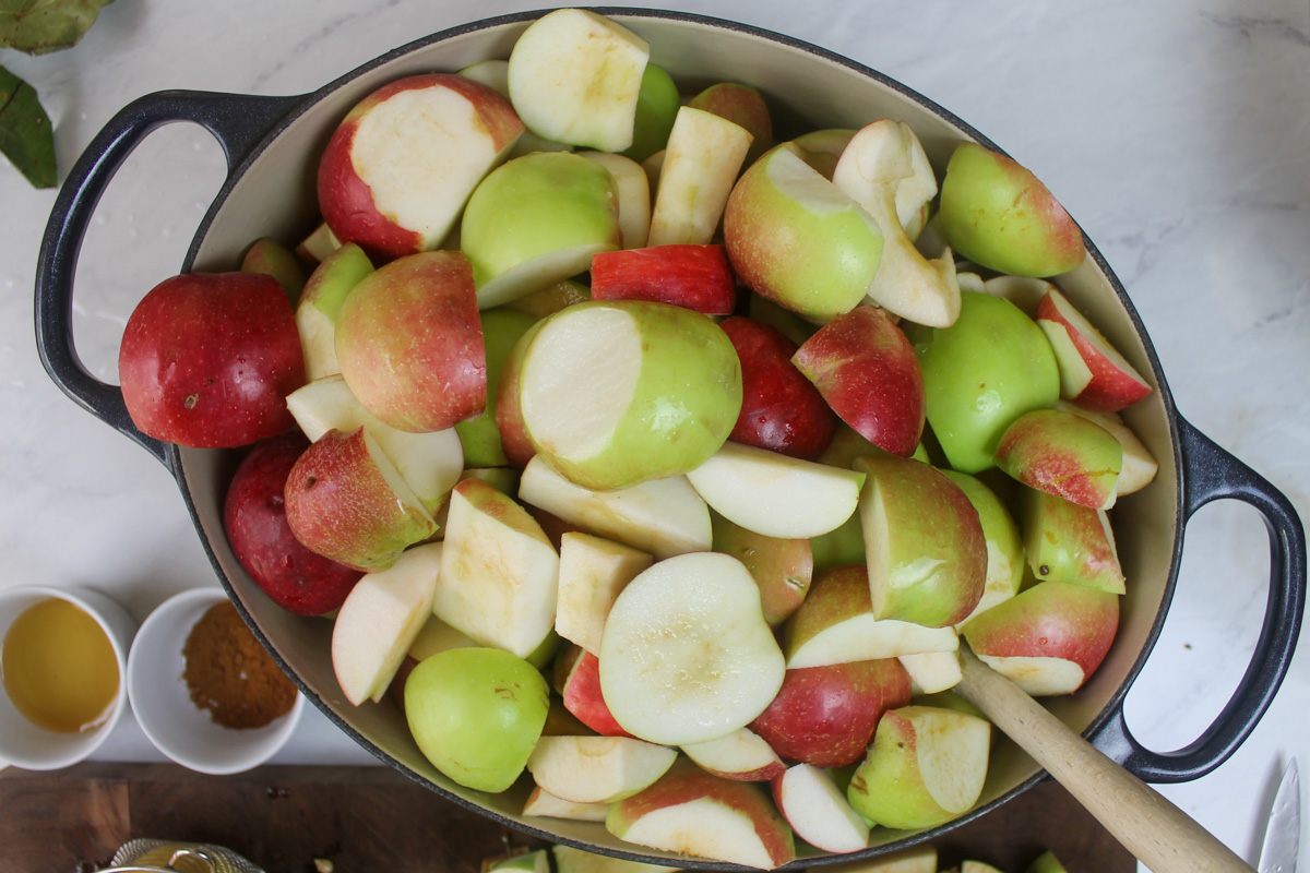 A large pot filled with raw cut apples ready to simmer for applesauce.